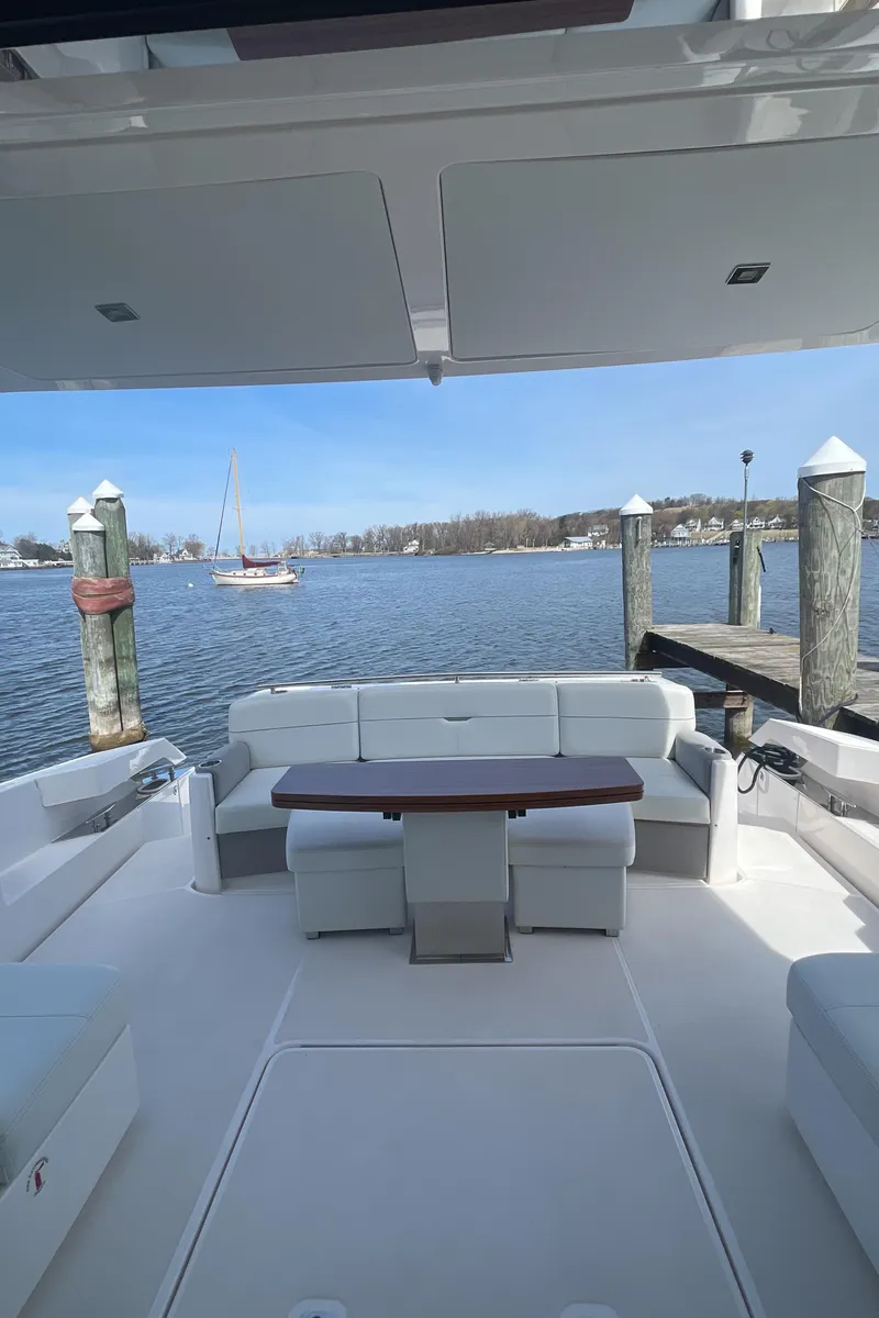 Slide: The Image of 2020 Tiara Yachts 53 Coupe, spacious deck with seating, docked by serene waters. - 38