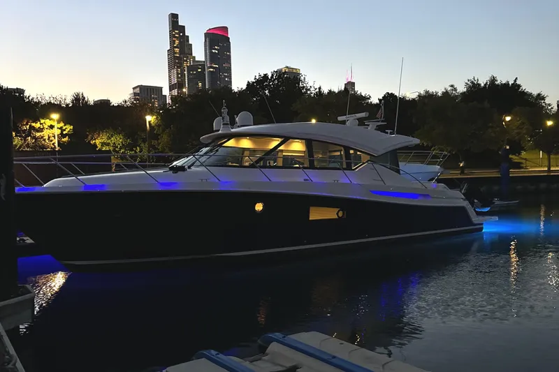Slide: The Image of 2020 Tiara Yachts C53 Coupe illuminated at dusk, city skyline in background. - 4