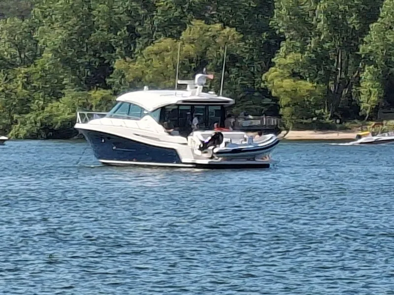 Slide: The Image of 2020 Tiara Yachts C53 Coupe cruising on a serene lake with lush green trees. - 42