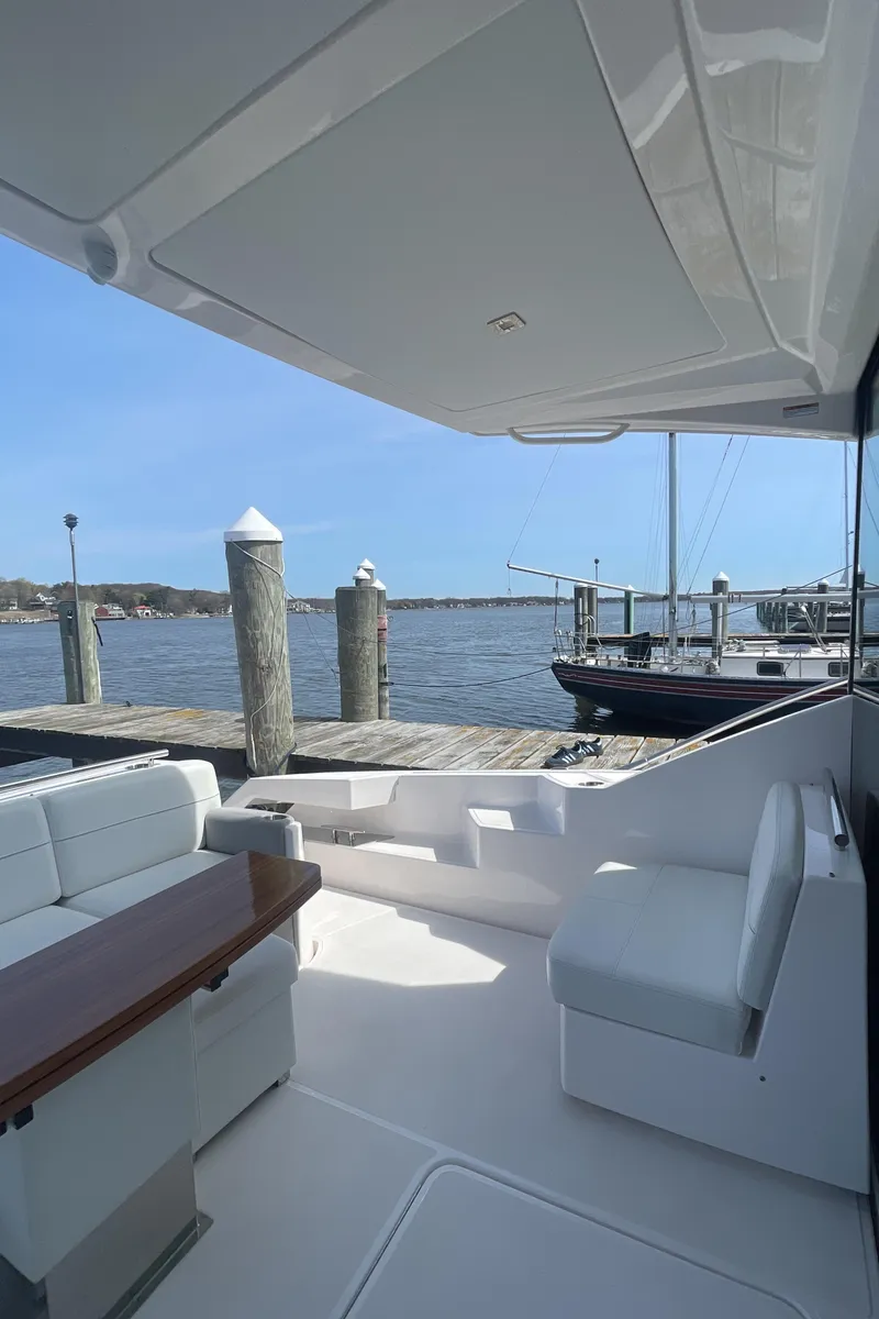 Slide: The Image of 2020 Tiara Yachts 53 Coupe, elegant deck view at marina with serene water backdrop. - 5