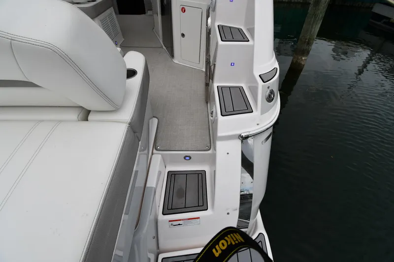 Slide: The Image of 2021 Regal 35 Sport Coupe boat interior with white seating and steps near water. - 28