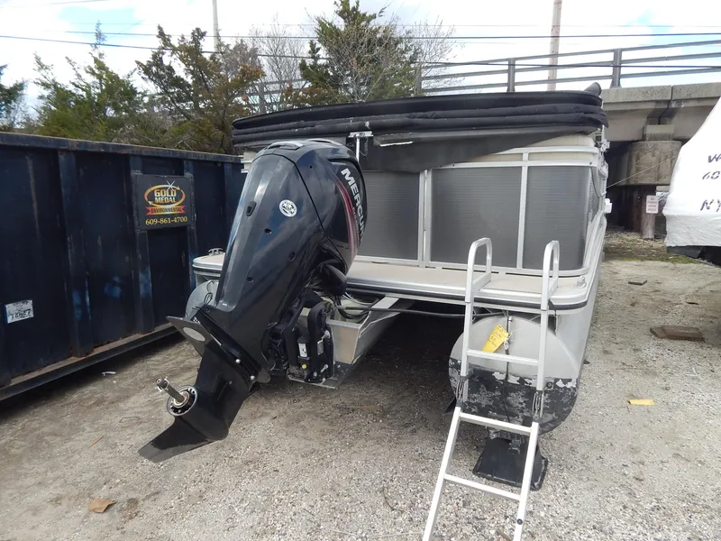 Slide: The Image of 2016 Cypress Cay Seabreeze 230 pontoon boat with Mercury outboard motor, parked on gravel. - 12