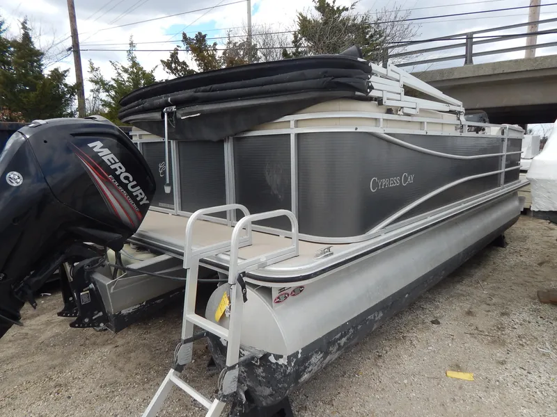 Slide: The Image of 2016 Cypress Cay Seabreeze 230 pontoon boat with Mercury outboard engine, parked on gravel. - 13