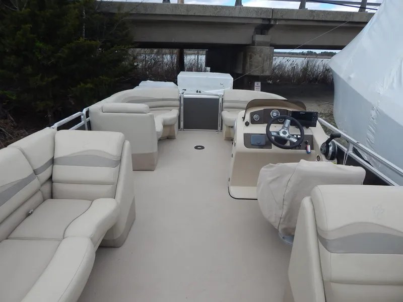 Slide: The Image of 2016 Cypress Cay Seabreeze 230 pontoon boat with beige seating and helm under a bridge. - 17