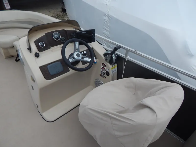 Slide: The Image of 2016 Cypress Cay Seabreeze 230 boat helm with covered captain's chair and steering wheel. - 18