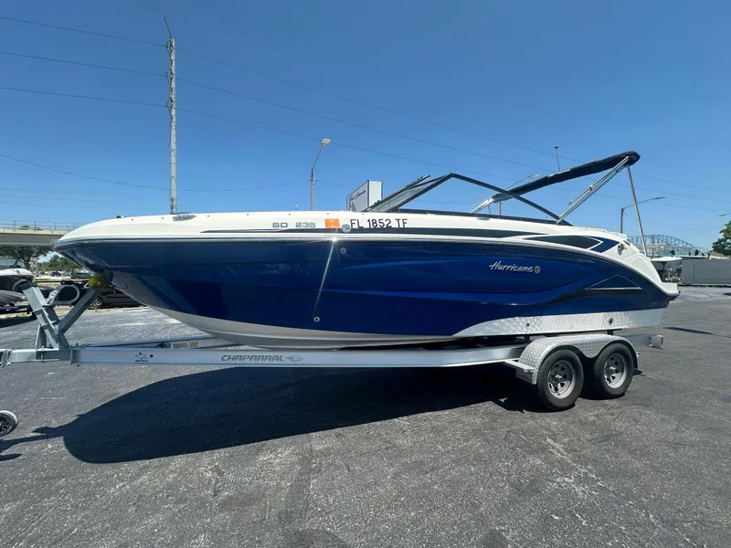 The Image of 2022 Hurricane SunDeck 235 OB boat on trailer, blue and white design, parked outdoors. - 1