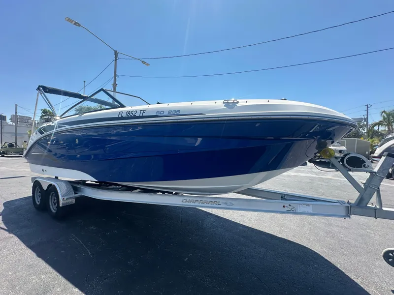 Slide: The Image of 2022 Hurricane SunDeck 235 OB boat on trailer, blue and white design, parked outdoors. - 7
