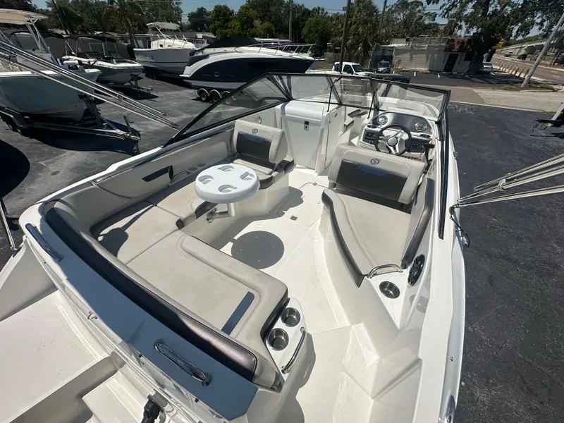 Slide: The Image of 2022 Hurricane SunDeck 235 OB boat with spacious seating and modern design in a marina setting. - 8