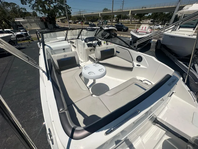 Slide: The Image of 2022 Hurricane SunDeck 235 OB boat with spacious seating and table, docked outdoors. - 9