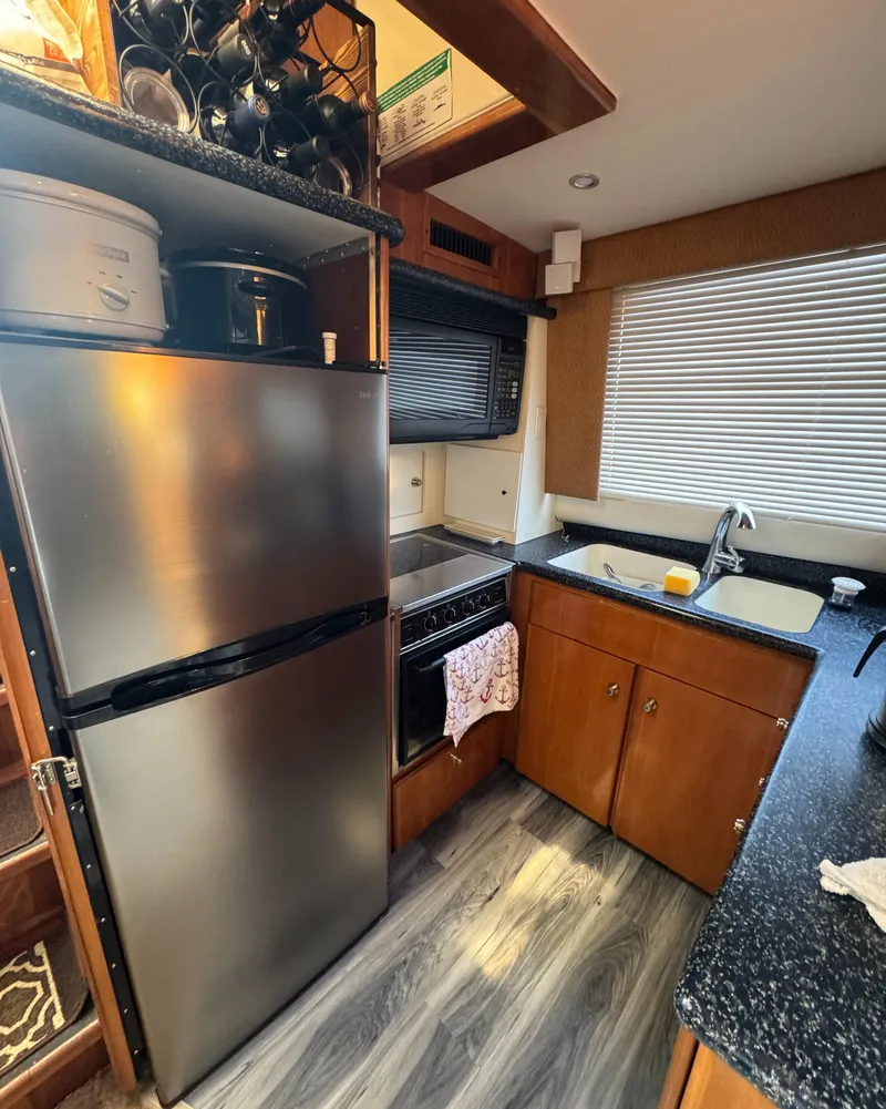 Slide: The Image of Kitchen area of 2000 Carver 504 Cockpit Motor Yacht with modern appliances and wood cabinetry. - 27