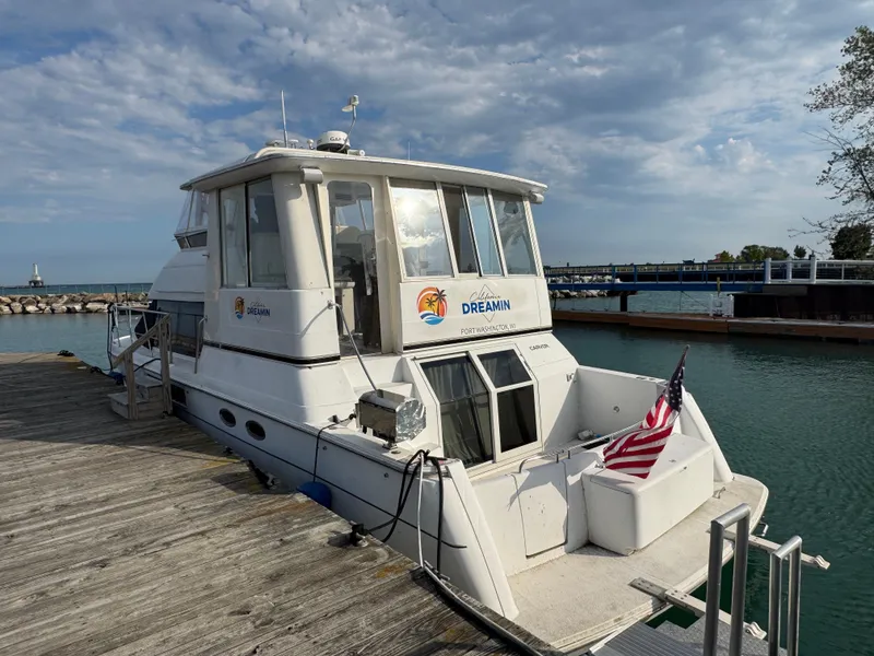 Slide: The Image of 2000 Carver 504 Cockpit Motor Yacht docked, featuring spacious deck and American flag. - 3