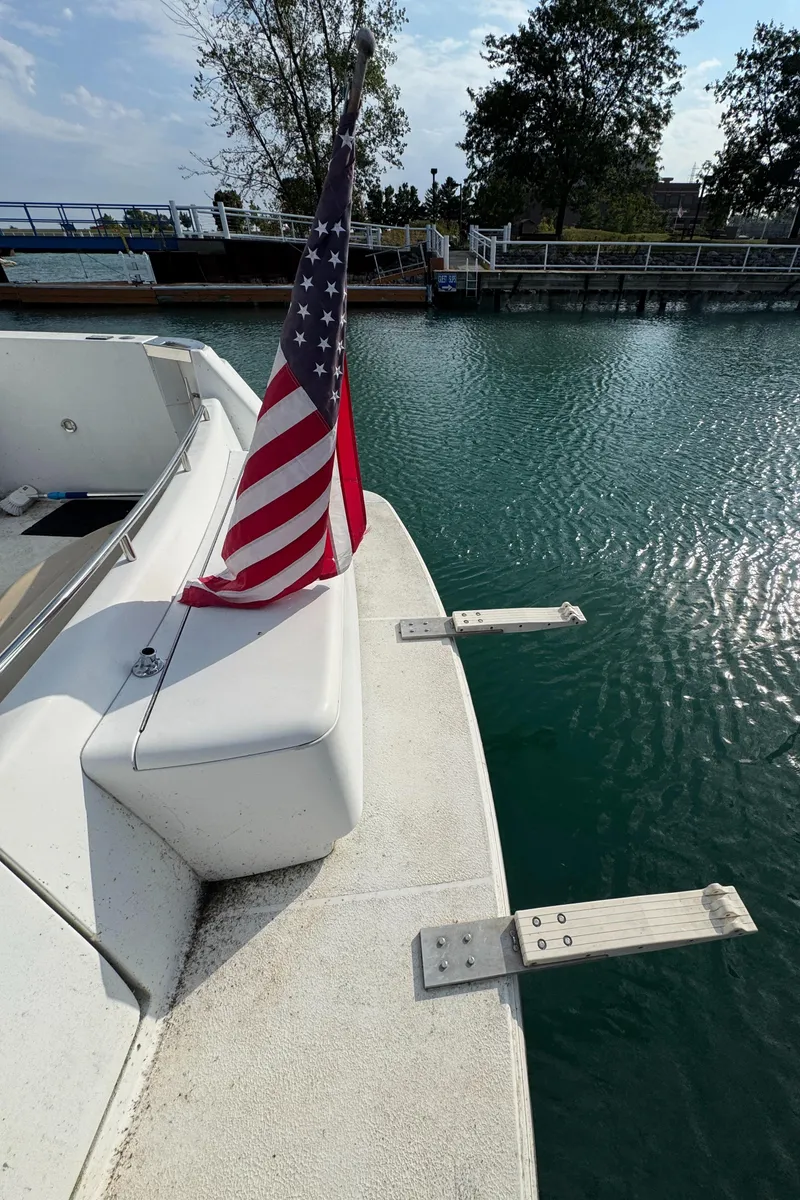Slide: The Image of Carver 504 Cockpit Motor Yacht 2000 with American flag, docked by calm waters. - 5