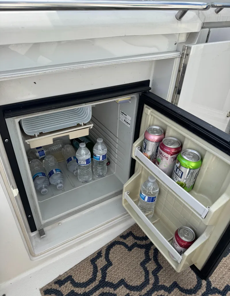 Slide: The Image of Mini fridge on 1994 Regal 322 Commodore boat, stocked with water bottles and soda cans. - 13