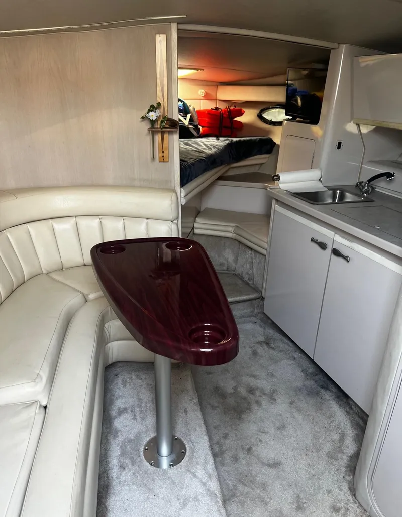 Slide: The Image of Interior of a 1994 Regal 322 Commodore yacht with seating, table, and kitchenette. - 16