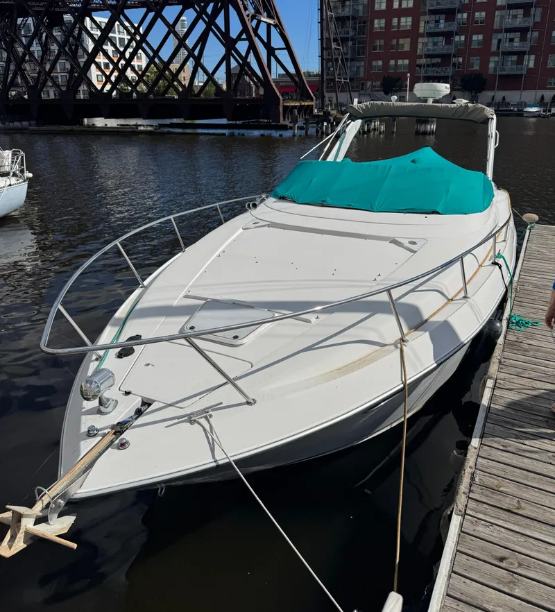 Slide: The Image of 1994 Regal 322 Commodore boat docked by urban waterfront with teal cover. - 2
