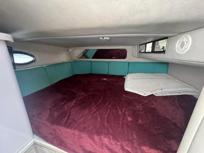 Slide: The Image of 1994 Regal 322 Commodore cabin with maroon bedding and teal cushions. - 25