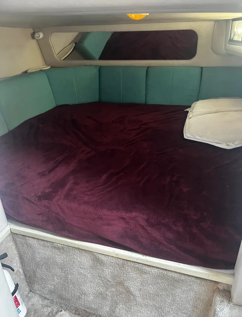 Slide: The Image of 1994 Regal 322 Commodore cabin interior with bed, teal cushions, and burgundy blanket. - 26
