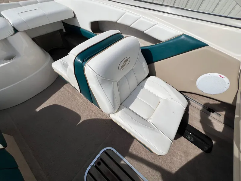 Slide: The Image of 1997 Starcraft 1810 boat interior with white and teal seating, speaker, and carpeted floor. - 14