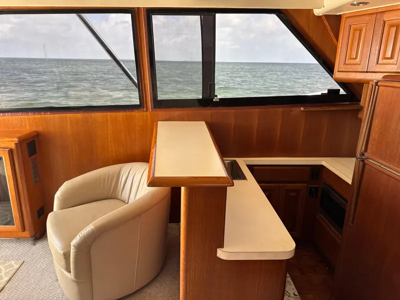 Slide: The Image of Interior of 1990 Viking 38 Convertible yacht with ocean view, featuring wood paneling and a leather chair. - 15