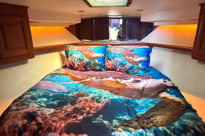 Slide: The Image of Cozy cabin bedroom in 1990 Viking 38 Convertible with vibrant ocean-themed bedding. - 16