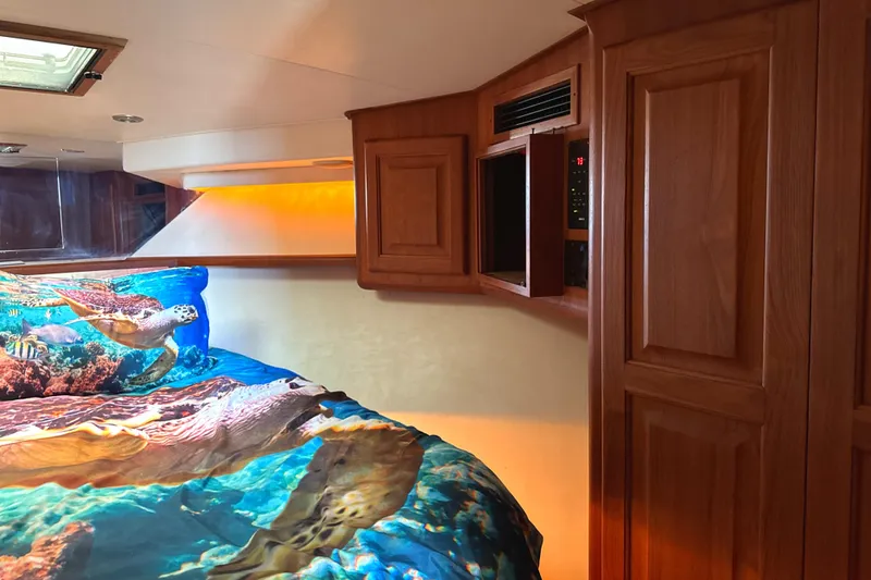 Slide: The Image of 1990 Viking 38 Convertible cabin with ocean-themed bedding and wooden cabinetry. - 18