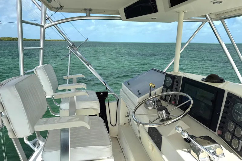 Slide: The Image of 1990 Viking 38 Convertible yacht helm with ocean view, featuring steering wheel and navigation controls. - 35