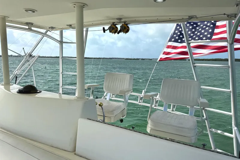 Slide: The Image of 1990 Viking 38 Convertible yacht deck with chairs and American flag, overlooking ocean. - 38