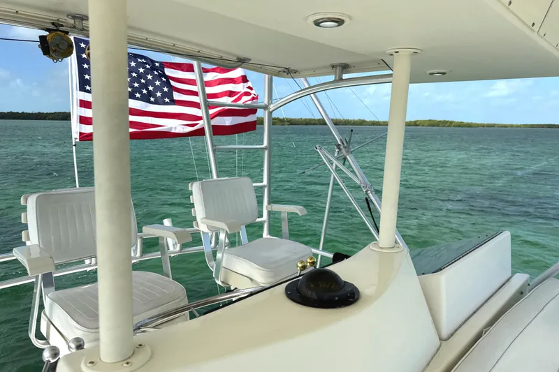 Slide: The Image of 1990 Viking 38 Convertible yacht with American flag, cruising on clear turquoise waters. - 39