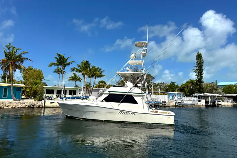 Slide: The Image of 1990 Viking 38 Convertible yacht on a sunny day, surrounded by palm trees and calm waters. - 4