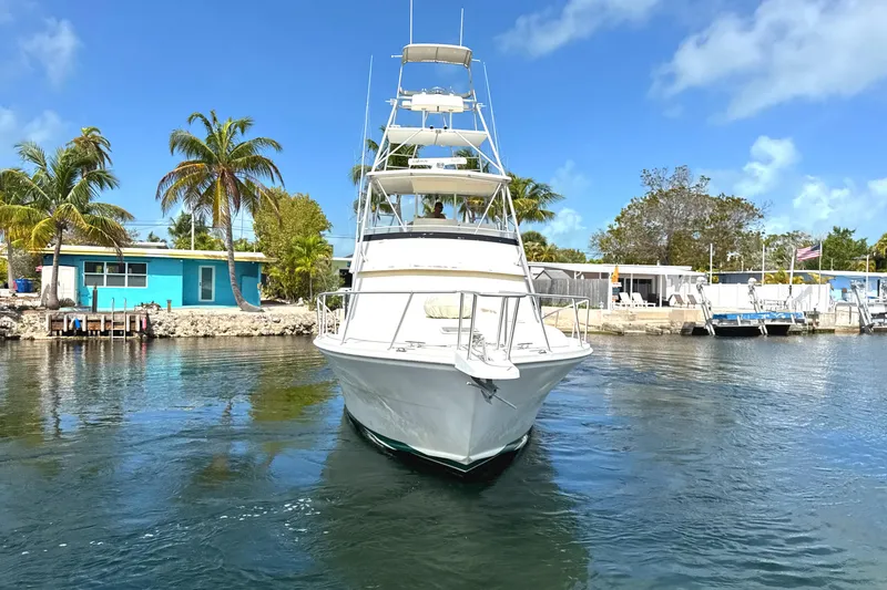Slide: The Image of 1990 Viking 38 Convertible yacht docked in a tropical marina setting. - 8