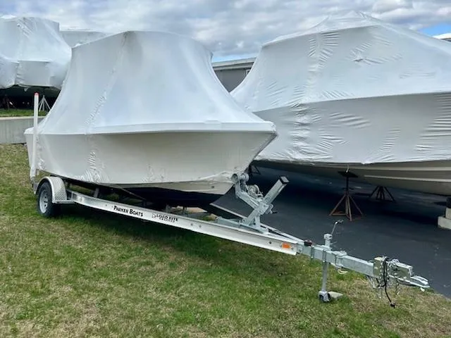 Slide: The Image of 2024 Parker 1801 Center Console boat covered on a trailer, parked on grass. - 2