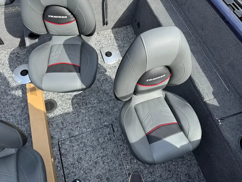 Slide: The Image of 2025 Tracker Pro Guide V-175 Combo boat seats, gray with red accents, on textured flooring. - 14