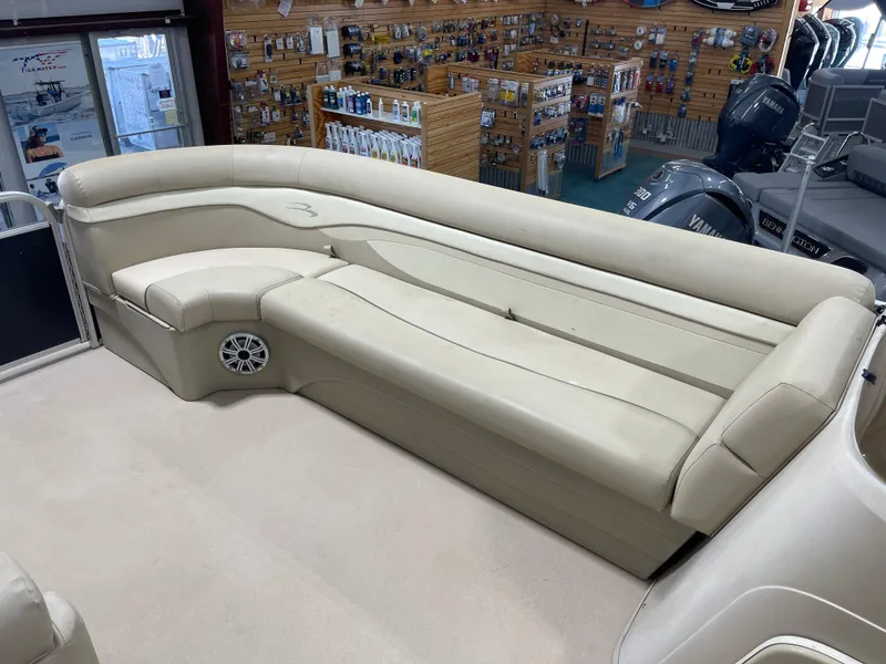 Slide: The Image of 2016 Bennington 22SX boat interior with beige seating and speaker, displayed in a showroom. - 21