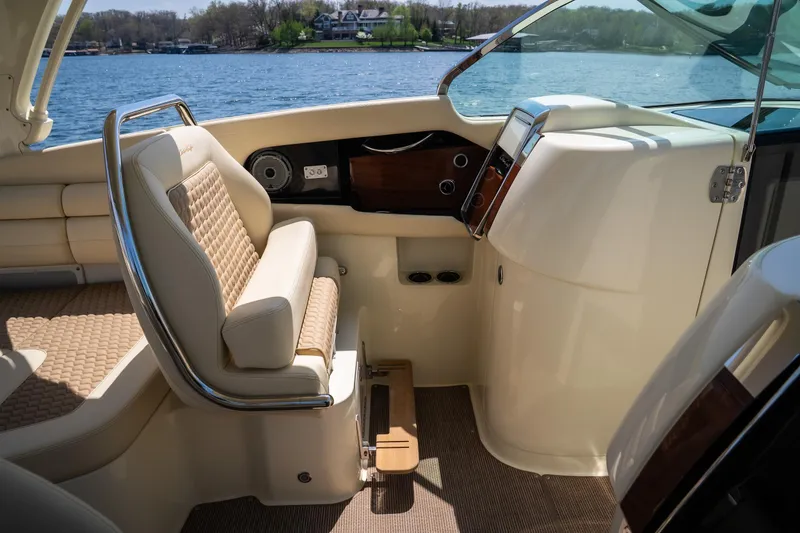 Slide: The Image of 2024 Chris-Craft Launch 35 GT interior with luxurious seating and dashboard, overlooking a serene lake. - 31