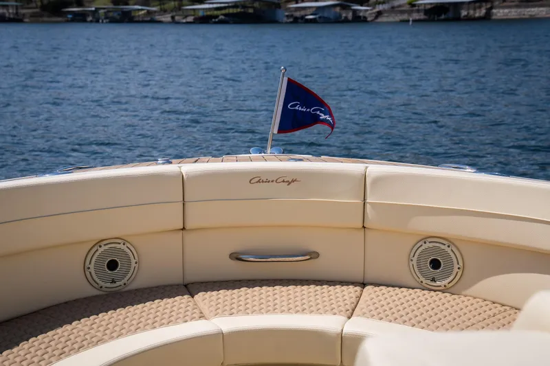 Slide: The Image of 2024 Chris-Craft Launch 35 GT boat with elegant seating and flag on a serene lake. - 38