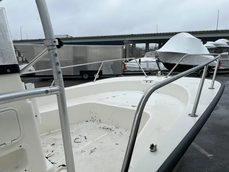 Slide: The Image of 2015 Boston Whaler 190 Montauk boat, docked, with visible railing and deck, overcast sky. - 8