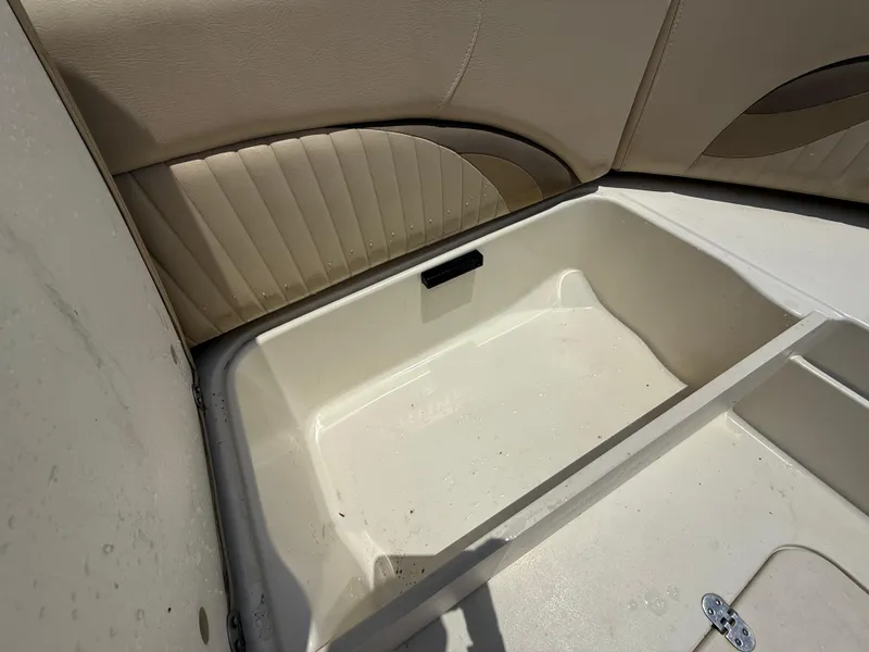 Slide: The Image of 2014 NauticStar 203DC Sport Deck storage compartment with beige upholstery. - 29