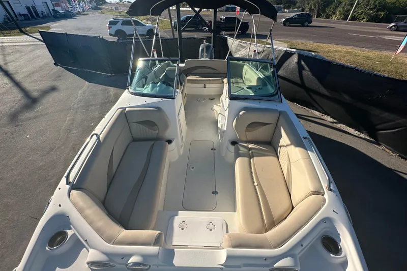Slide: The Image of 2014 NauticStar 203DC Sport Deck boat with beige seating and windshield, parked outdoors. - 39