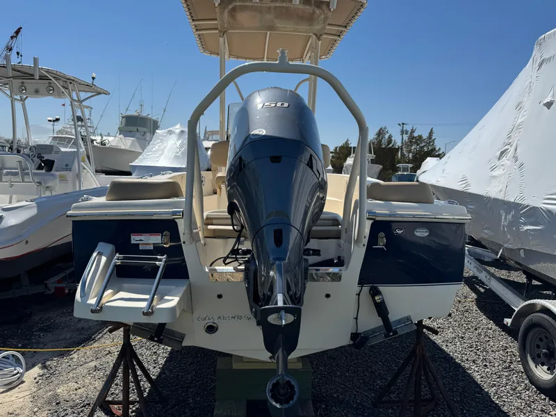 Slide: The Image of 2023 Scout 195 Sportfish boat with powerful outboard motor, parked on gravel lot. - 4