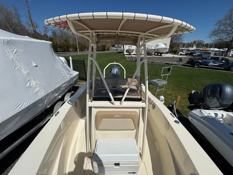 Slide: The Image of 2023 Scout 195 Sportfish boat with T-top and cooler, parked outdoors. - 7