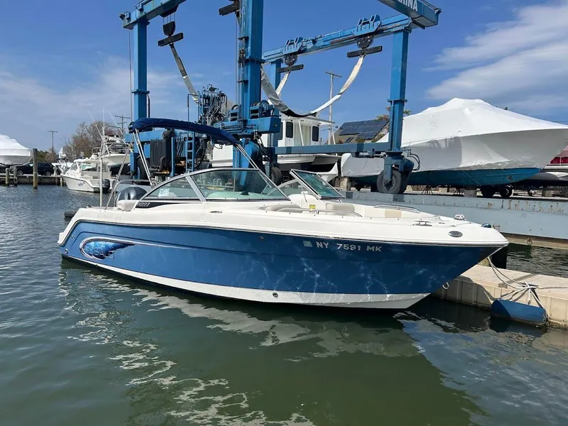 Slide: The Image of 2014 Robalo R227 boat docked at marina, blue and white design, clear sky background. - 0