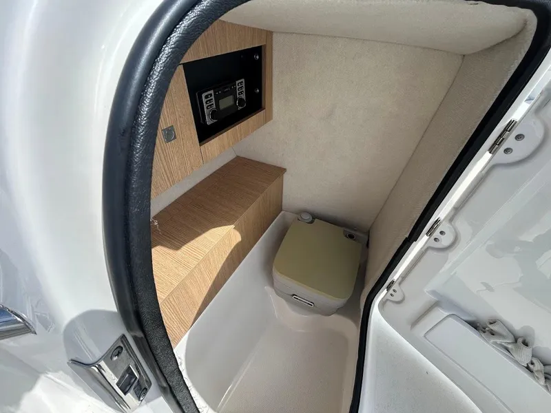 Slide: The Image of 2014 Robalo R227 boat interior with compact bathroom and control panel. - 24