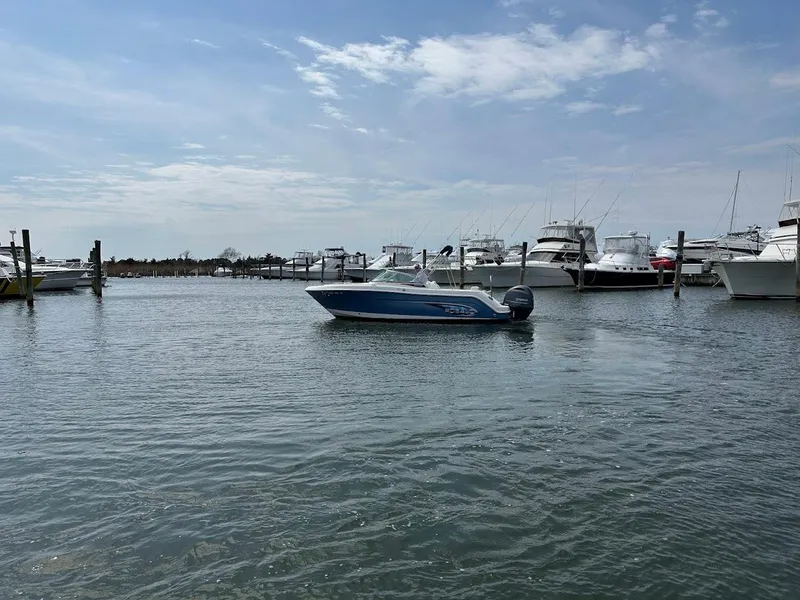 Slide: The Image of 2014 Robalo R227 boat on calm water with marina and cloudy sky background. - 4