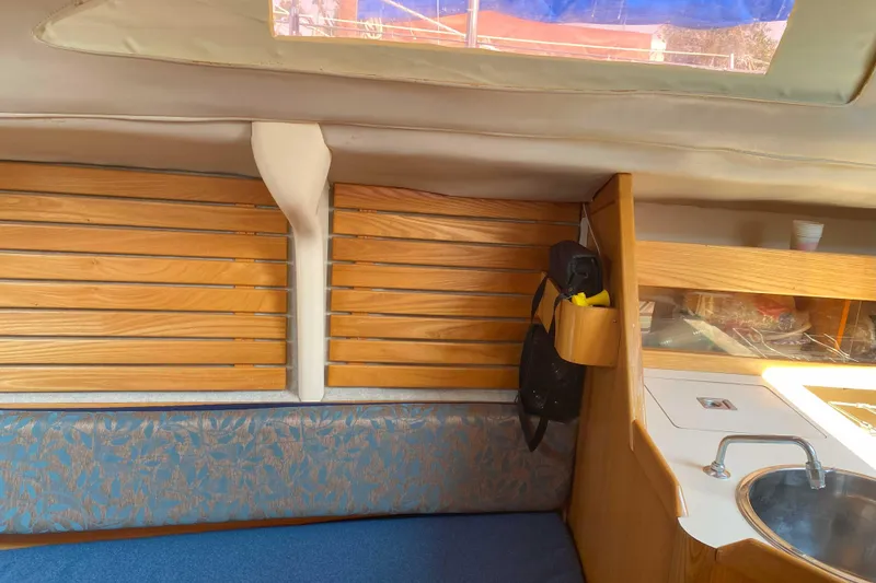 Slide: The Image of Interior of a 1988 Kirie 286 sailboat with wooden paneling and compact kitchen area. - 10