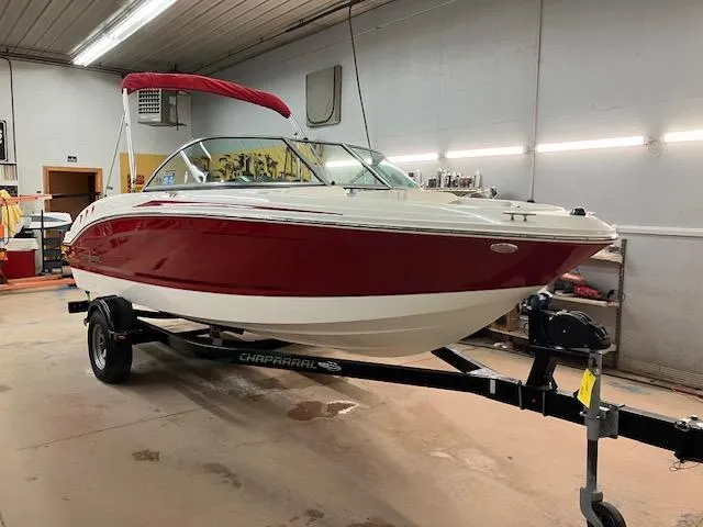 Slide: The Image of 2014 Chaparral 18 Sport H2O boat with red and white design on a trailer in a garage. - 2