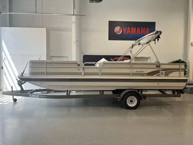 Slide: The Image of 1997 Hurricane 226 RE OB pontoon boat on trailer in showroom with Yamaha sign. - 2