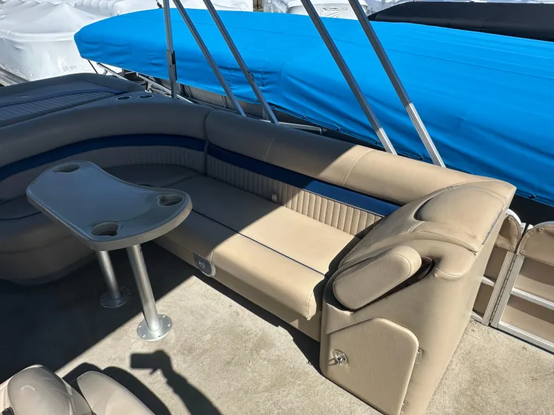 Slide: The Image of 2008 Godfrey AquaPatio 22 boat interior with beige seating and a small table. - 10