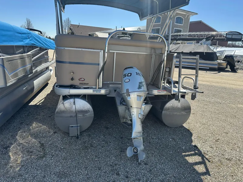 Slide: The Image of 2008 Godfrey AquaPatio 22 pontoon boat with outboard motor, parked on gravel. - 18