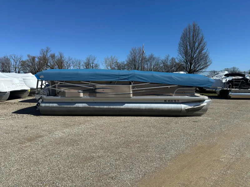 Slide: The Image of 2008 Godfrey AquaPatio 22 pontoon boat with blue cover, parked on gravel lot. - 3