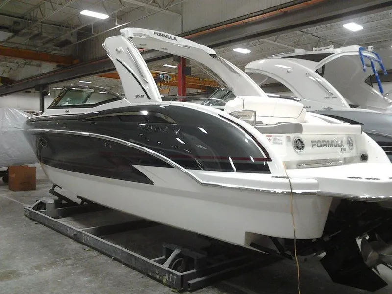 Slide: The Image of 2018 Formula 310 Bowrider boat in a showroom, sleek design with black and white exterior. - 10